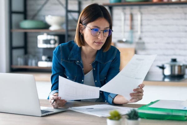 Request Certificate - Woman Working from her Kitchen Table Gathering Insurance Documents
